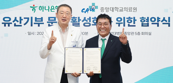 ▲김진우 하나은행 중앙영업그룹 부행장(오른쪽)과 이철희 중앙대학교의료원장이 4일 중앙대학교병원 중앙관 5층 회의실에서 협약서를 들고 기념촬영을 하고 있다. / 사진=하나은행 하나은행, 중앙대학교의료원과 유산 기부 활성화 위한 업무협약 체결